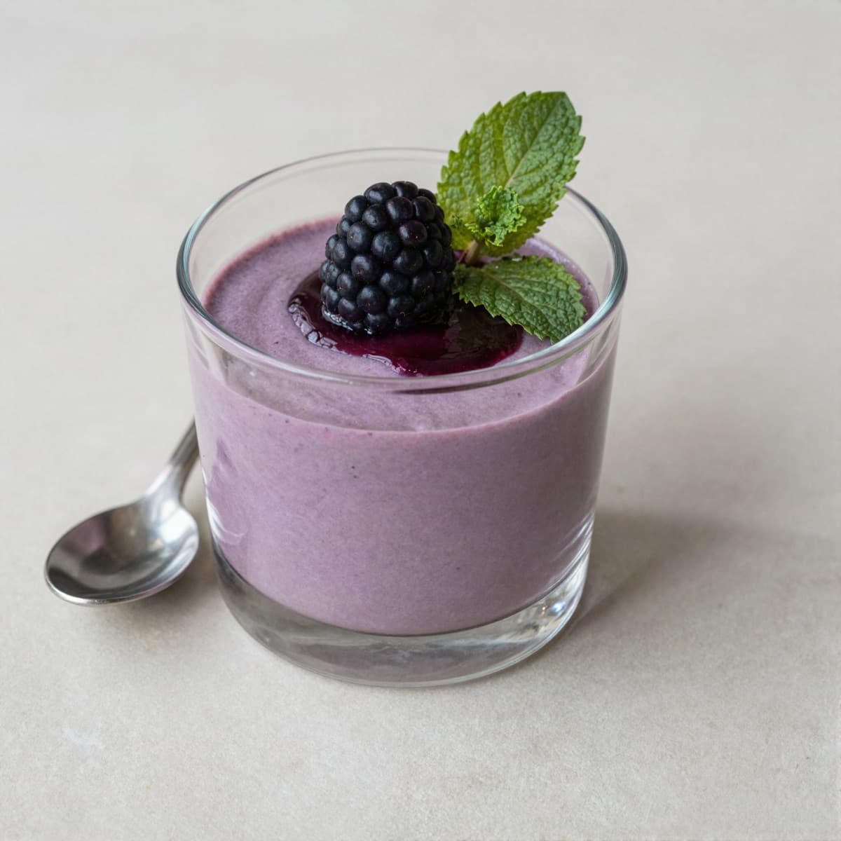 Vaso individual de mousse de mora con una mora fresca y menta